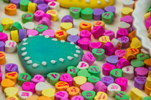 A heart shaped cookie surrounded by colorful heart shaped candies.