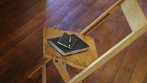 notepad, pen, and Bible in a wooden chair 