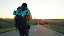 Concept of traveling. Woman hiking in mountains enjoying success. Rear view of female hipster walking along rocky area on sunset. Modern person with backpack. Hiking walking slow motion activity.