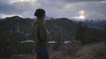 a woman standing outdoors alone taking in a mountain view 