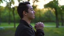 a man reverently praying outdoors 