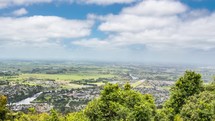 Clouds moving fast in sunny day over green urban country in New Zealand nature Time-lapse
