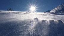 Windy day in frozen winter alps mountains nature with snow blown by wind
