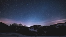 Magic blue night sky with million stars of milky way galaxy and sunrise in winter mountains nature Night to Day Time-lapse
