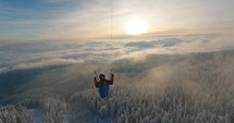 Paragliding Flying Dream freedom above foggy winter forest mountains at sunset
