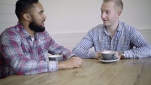 two men having a conversation over coffee 