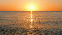 sun shining over calm water at sunset 