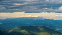 Clouds sky moving fast over green forest mountains landscape time lapse
