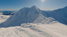 Frozen winter alps snowy mountains in sunny day with blue sky, tilt up reveal shot, adventure mountaineering

