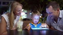 Family with tablet PC in outdoor cafe
