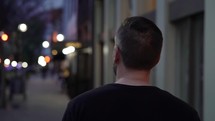 man walking on sidewalk alone at night 