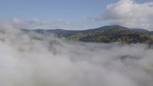 Fly above clouds over green nature
