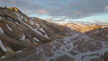 Aerial view of Icelandic rainbow snowy mountains with river delta in sunset evening
