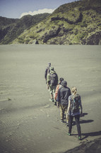 line of people backpacking on a beach 