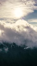 Vertical video of Fluffy clouds moving fast over spring mountain range in sunny nature landscape Timelapse
