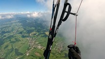 Flying by the clouds on paragliding above green landscape in summer adrenaline adventure
