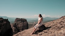 Woman sitting on the top of a mountain