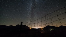 Time lapse of a dolly shot over a fence on a starry night sky with milky way galaxy
