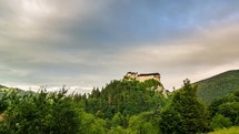 Clouds over historic castle in green forest country in evening Time lapse
