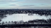 Aerial push-in drone shot of Riverdale Park East in vibrant Toronto eastside neighborhood on a cold winter day. People sliding in the snow while aircraft is flying over Don Valley Parkway.