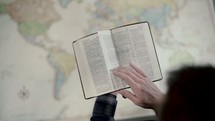 a man reading a Bible over a map 