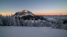 Colorful winter sunset over snowy mountains peak time lapse zoom in
