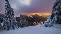 Winter mountains time lapse of colorful clouds motion fast over snowy forest trees in morning sunrise nature
