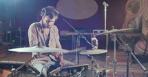 Drummer playing on electronic drum set in a recording studio