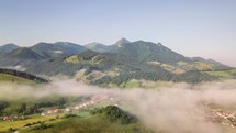 Foggy morining in green mountains over rural country. Aerial Time lapse
