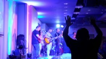 musicians on stage and hands raised during a worship service 