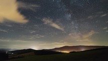 Stars sky with milky way galaxy and clouds moving over beautiful landscape time lapse
