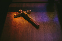 Crucifix sitting in colored light on a pew in a Roman Catholic church