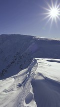 Vertical panorama of snowy winter alps mountains in beautiful sunny day with snowdrift in foreground
