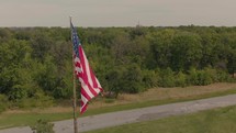 American flag on a flagpole by a river 