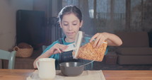 young girl eating morning cereal with milk for breakfast