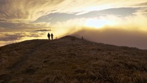 Tourists looking at beautiful sunrise in misty mountains nature in autumn morning

