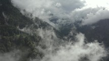 Aerial view flying through clouds in the mountains.