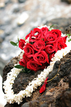 Bouquet of red roses and a lei on a rock