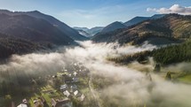 Aerial view of misty countryside valley in alpine mountains in sunny autumn nature time lapse hyperlapse

