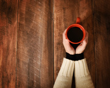 women holding a coffee mug over a wood table 