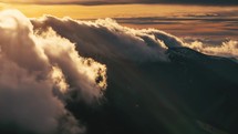 Mystic fluffy clouds moving down in alps mountain range in katabatic foehn wind at golden sunset time lapse
