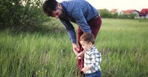 father and son playing in tall grass