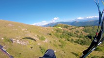 Paragliding flight adventure above grassy mountains and forest in sunny autumn nature
