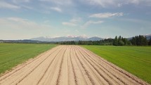 Aerial view of Plowed food field under alps mountains in rural farm country fresh spring nature farmland
