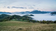 Foggy morning with clouds moving over country with sheep farm before sunrise in autumn mountains time lapse
