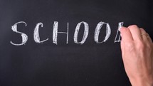 Bold white chalk letters spell School. Inscription SCHOOL. Chalk writing on blackboard. Concept of beginning of school year.	