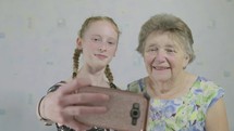 caucasian grandmother and granddaughter taking a selfie 
