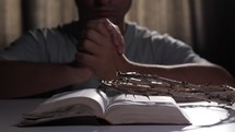 Believer praying with crown of thorns on Bible