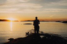a man fishing on a shore at sunrise 
