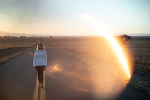 woman standing in the middle of a country road 